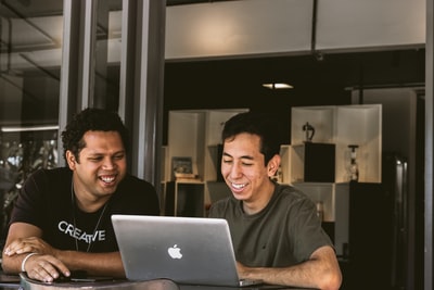 两个微笑的男人看着MacBook